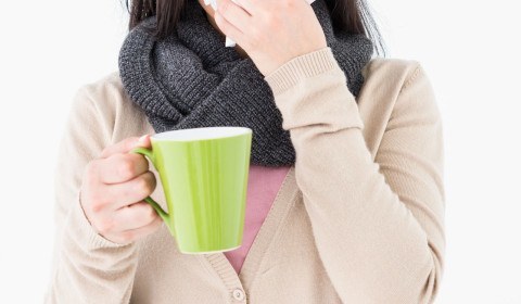 A woman sneezed as she holds her coffee