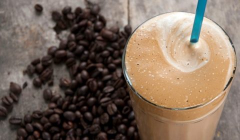 A protein shake surrounded by coffee beans